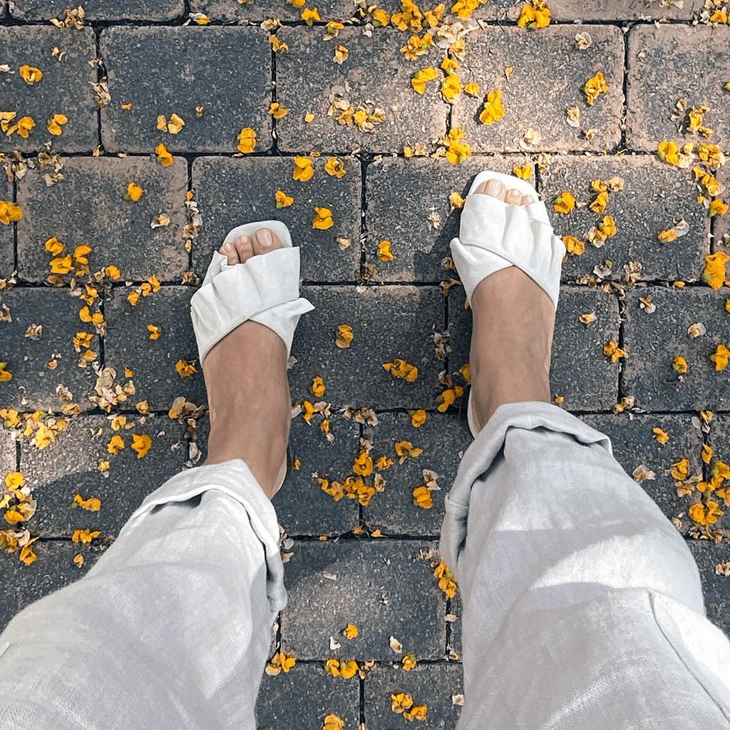 Mujer usando sandalias Calm Ivory de Sabinis en ante marfil, caminando cómodamente, en una escena de estilo primavera verano.